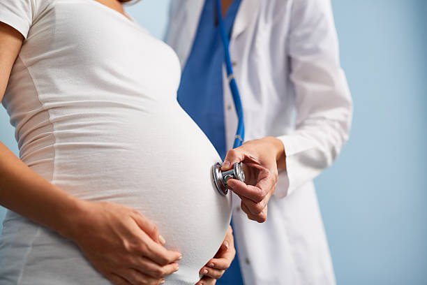 Doctor listening breath of baby in pregnant female abdomen Doctor listening breath of baby in pregnant female abdomen